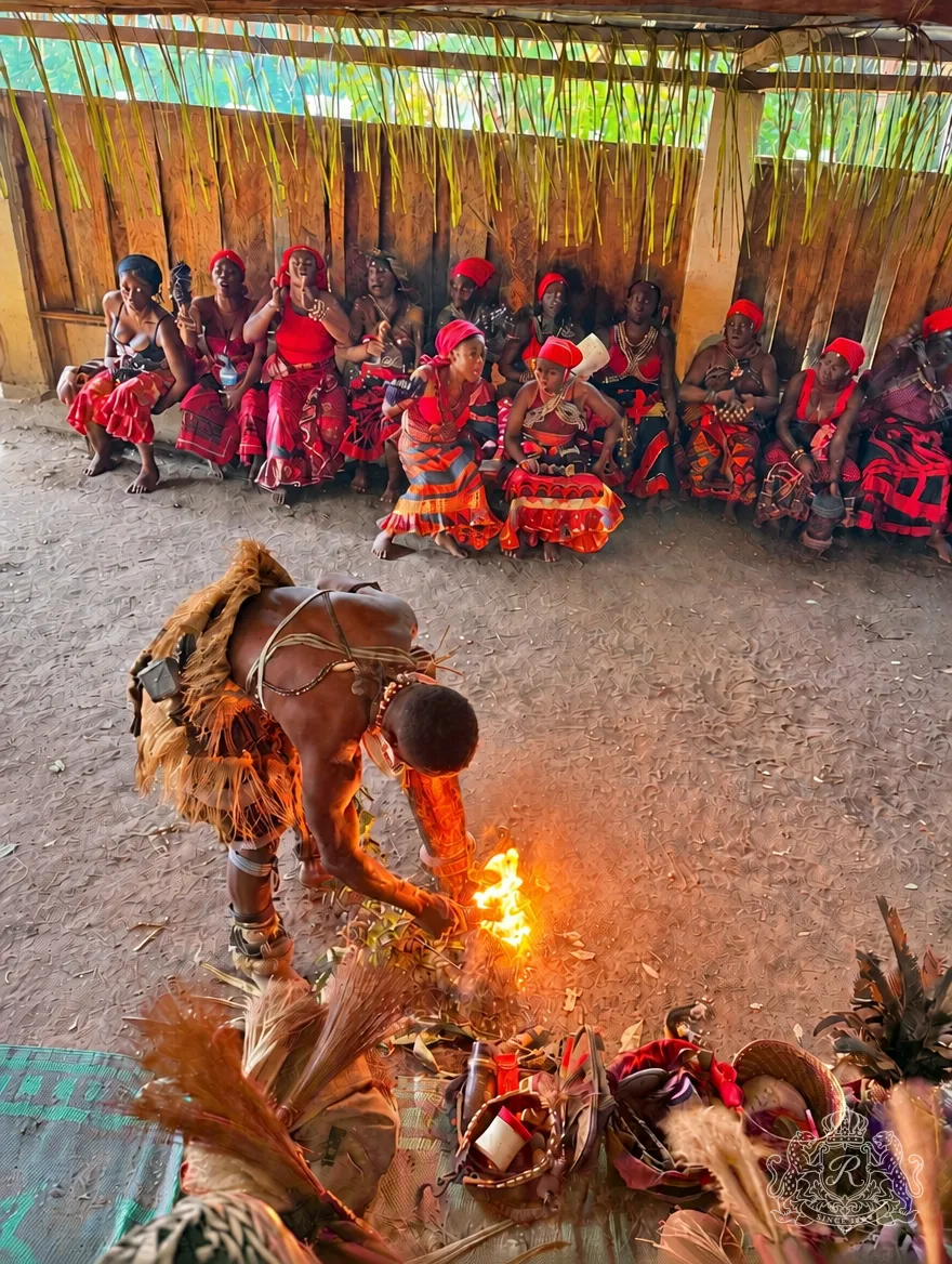 Homme allumant le feu rituel dans le temple, femmes en rouge chantant le long du mur