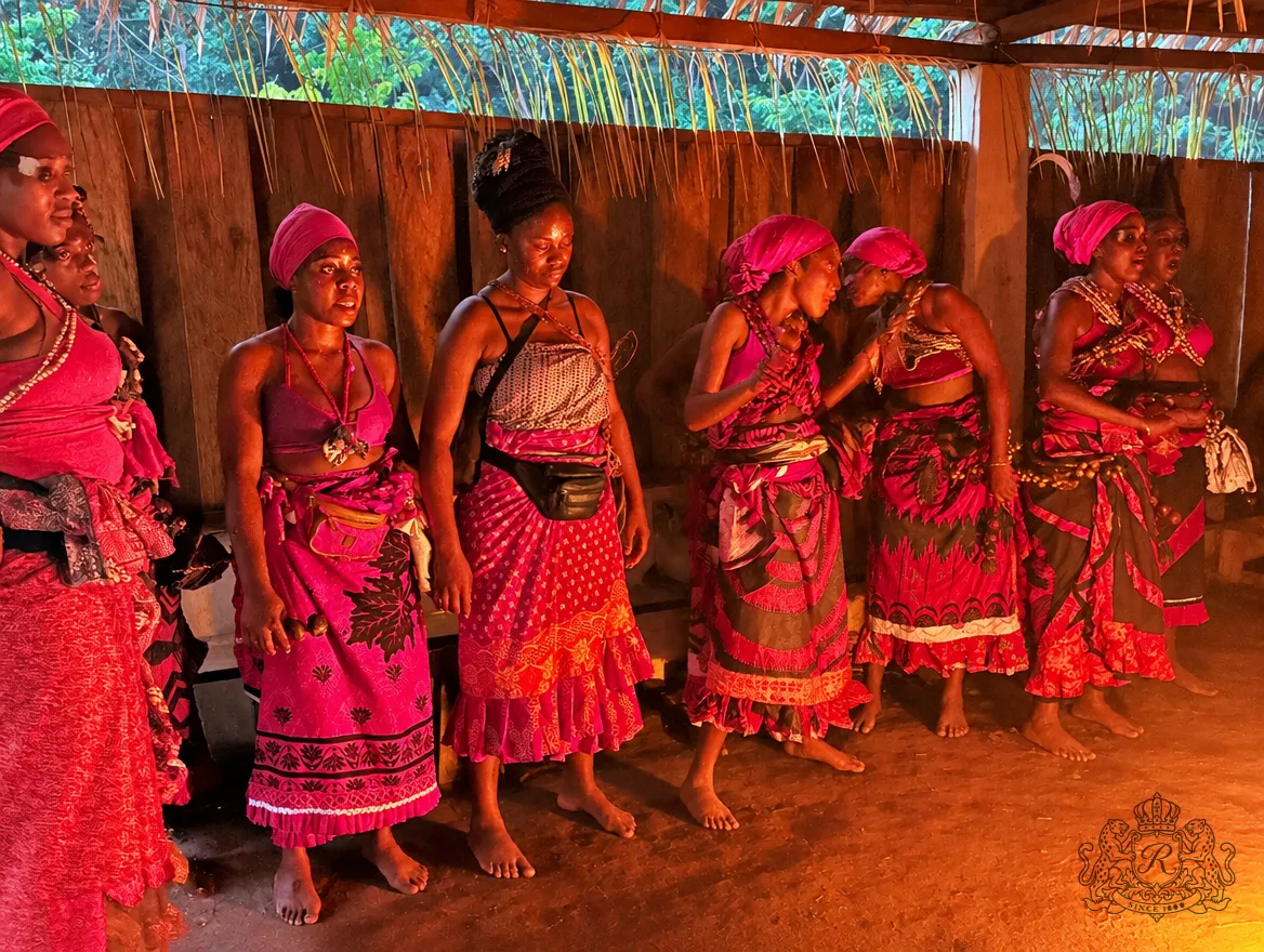 Femmes en pagnes et coiffes rouges chantant côte à côte dans le temple