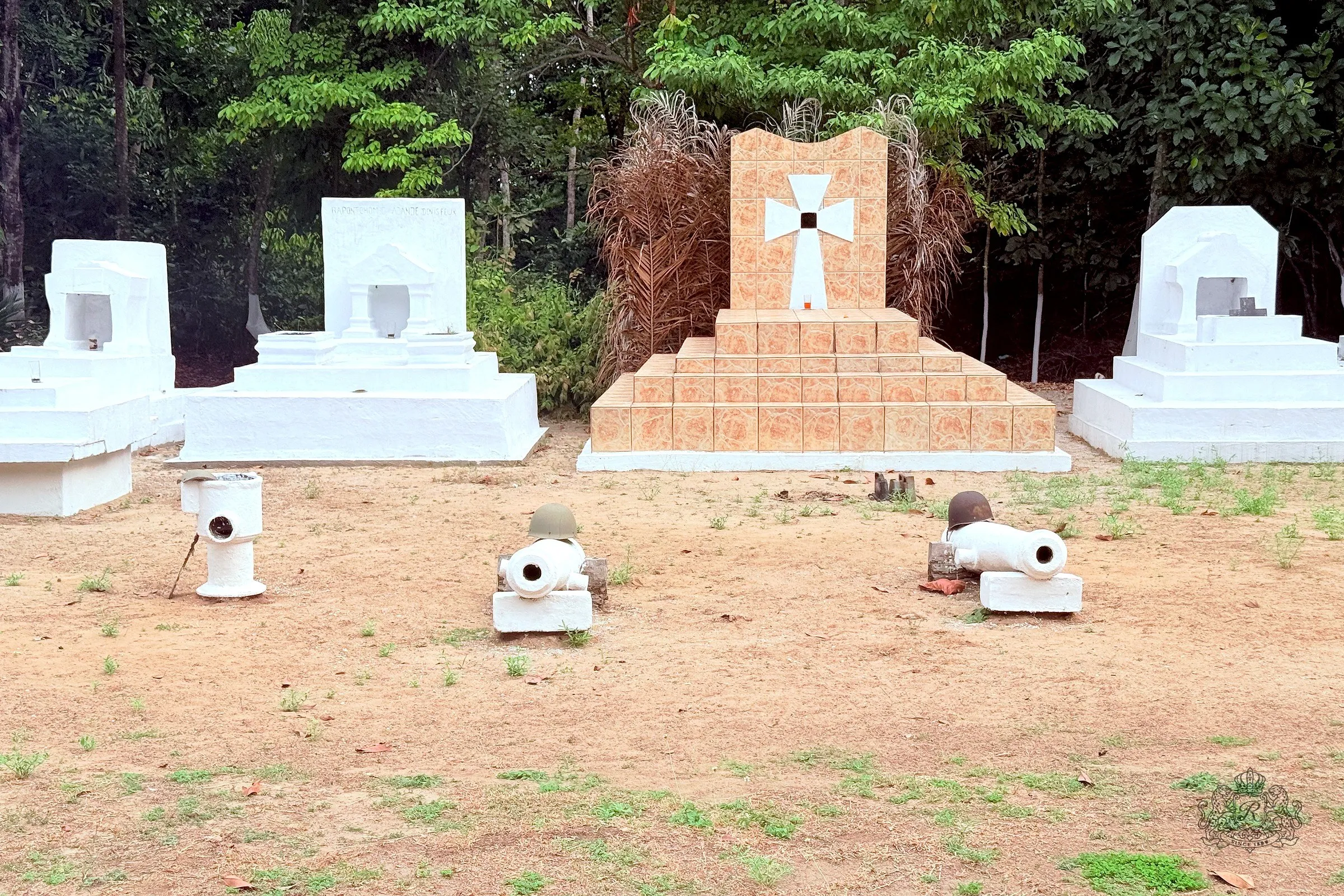 Devant la tombe du roi Denis, carrelée et marquée d'une grande croix blanche, trois canons anciens peints en blanc, deux d'entre eux coiffés d'un casque militaire