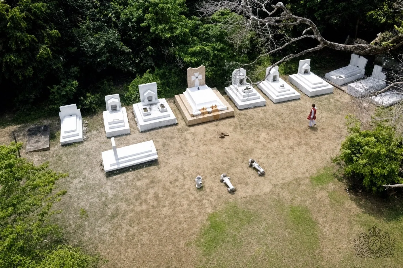 Vue aérienne de la sépulture royale d'Iwounwé : une rangée de tombes blanches en lisière de forêt, la tombe du roi Denis au centre