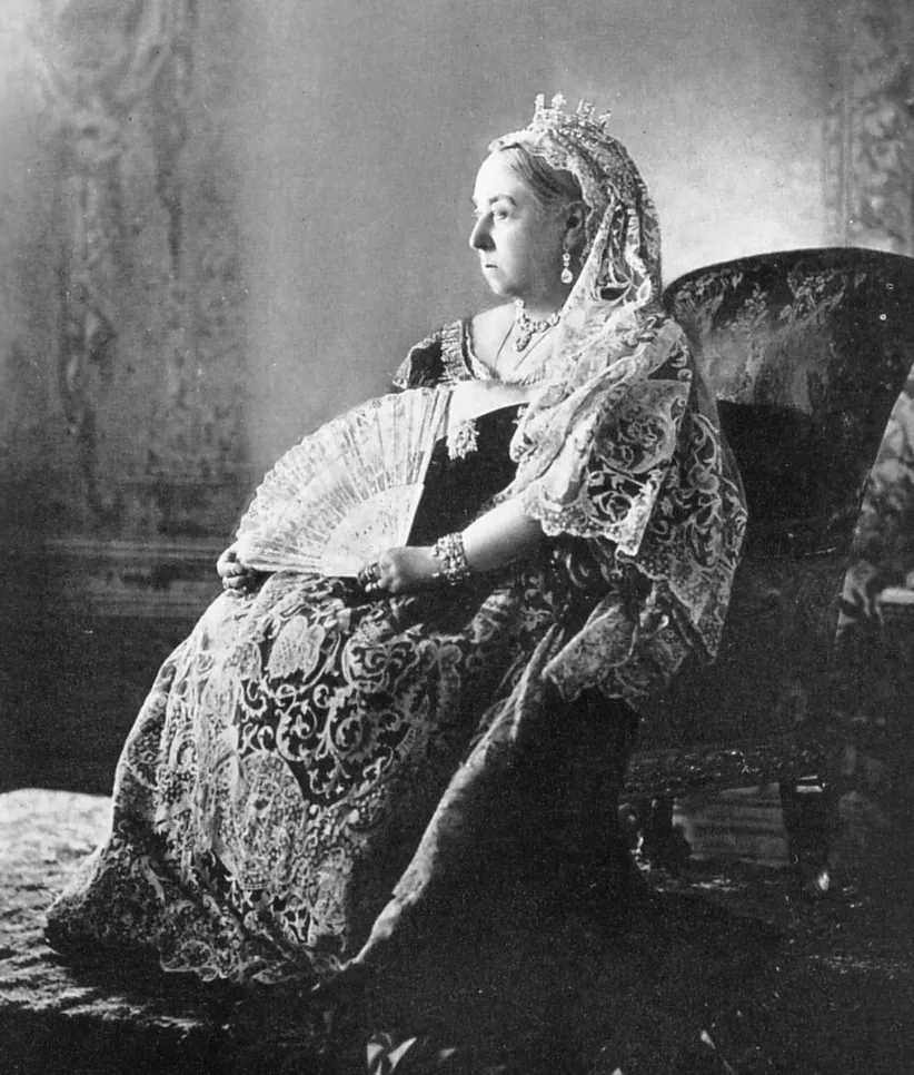 Photographie de la reine Victoria âgée, assise, coiffée d'un petit diadème et d'un voile de dentelle, un éventail à la main